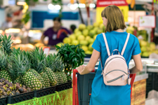 A women in a blue dress shopping for produce.