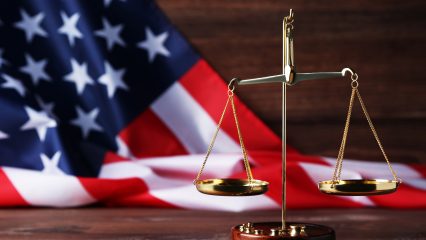 Scales of justice with american flag on brown wooden table