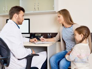 Woman and child looking at doctor while signing a paper.