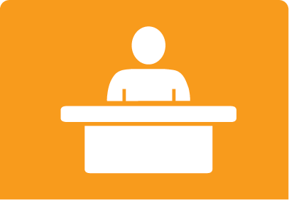 Orange and white icon with a desk and a person/figure behind the desk.