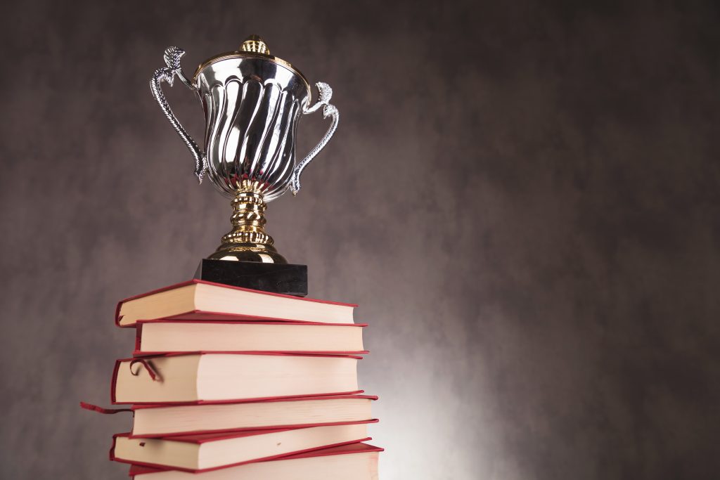 trophy cup on a pile of books with copyspace, studio picture